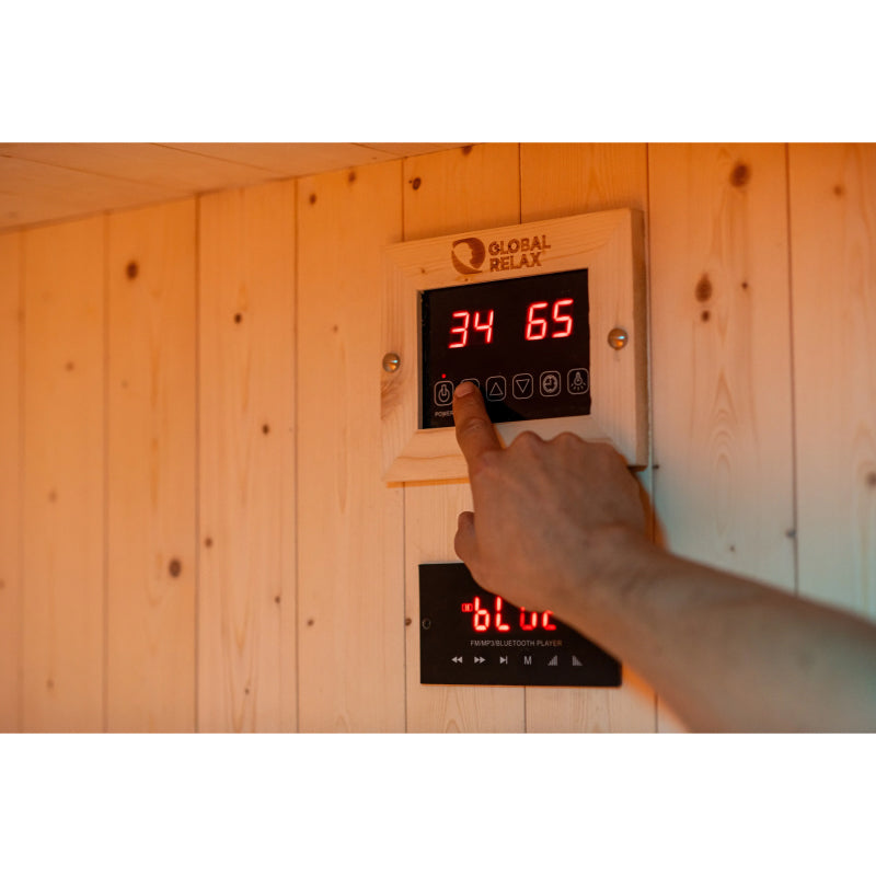 Hand pressing a digital control panel on a wooden wall with 'Global Relax' branding.