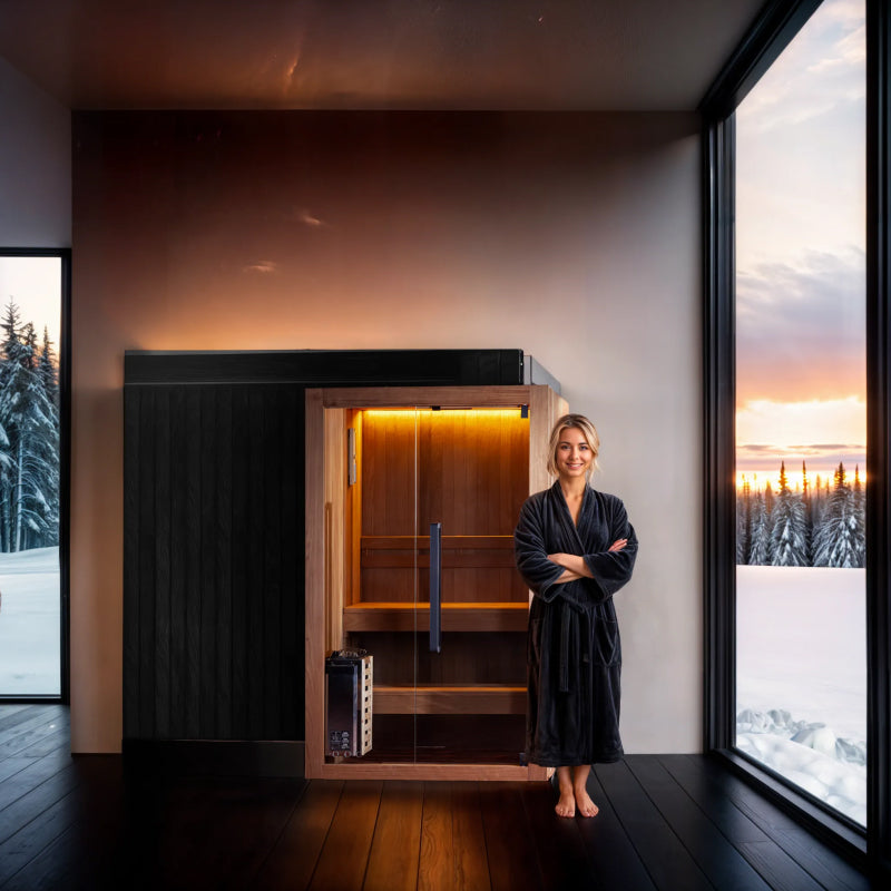 Woman in a black robe standing in front of a sauna in a modern room with large windows showing a snowy landscape.