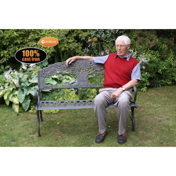 Gardeco Cast Iron Bench With Tree In A Garden Setting With A Man Sitting On It | SKU: BENCH-TREE | Barcode: 5031599039459