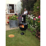 Gardeco Sempra Large Black Chimalin AFC Chiminea With Burning Logs Inside In A Garden Setting With A Man | SKU: AFC-C21.75 | Barcode: 5031599044613